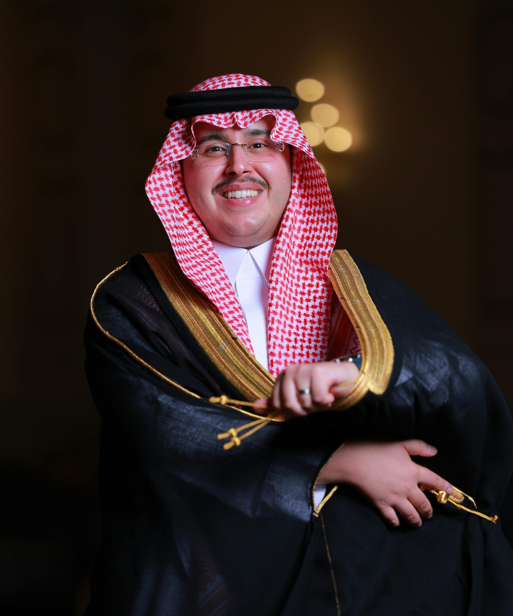 A smiling man in traditional Saudi clothing, embodying cultural elegance and celebration.